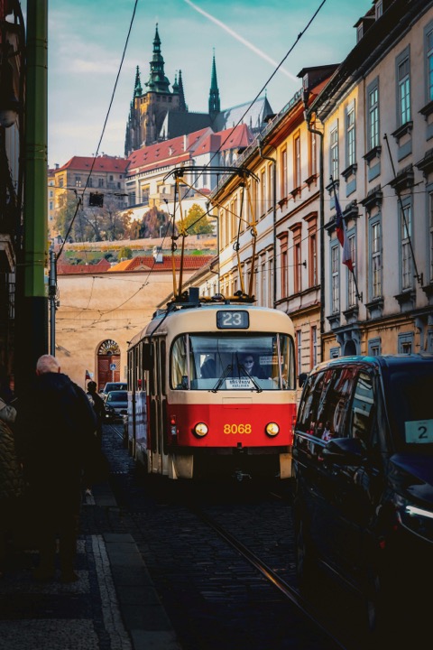 Eine rot-weiße Straßenbahn der Linie 23, dahinter die Prager Burg