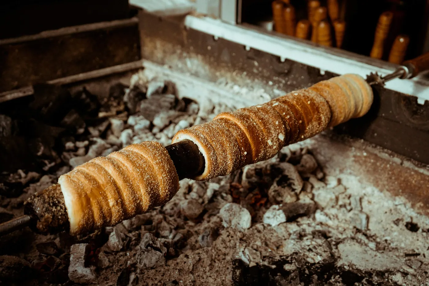 Trdelník dreht sich über der Glut eines Marktstands