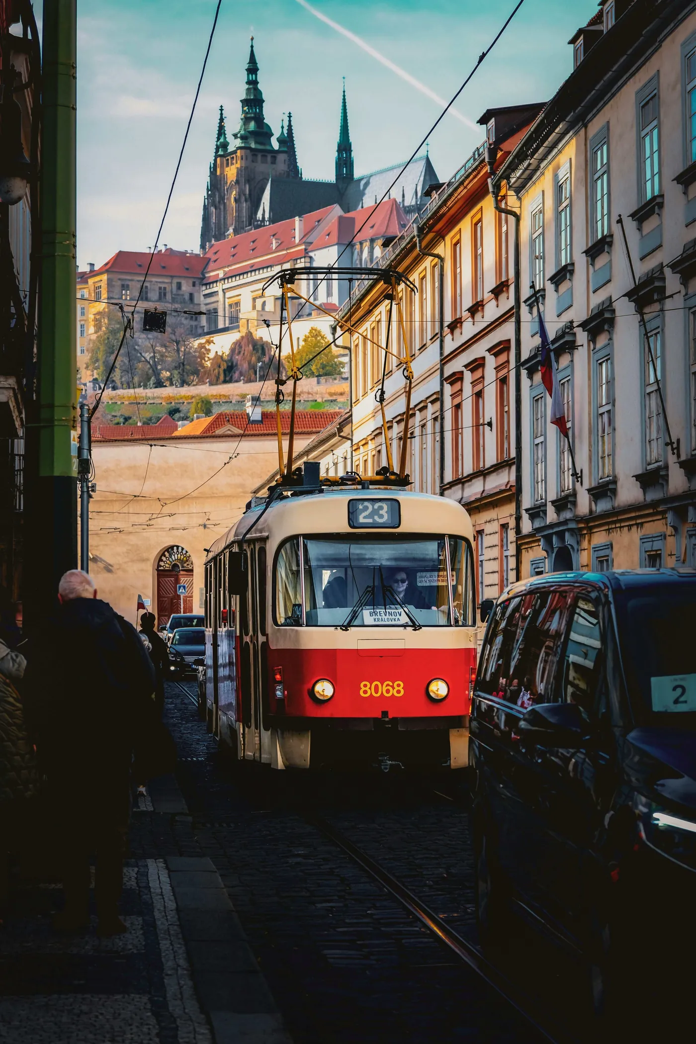 Eine rot-weiße Straßenbahn, dahinter die Prager Burg