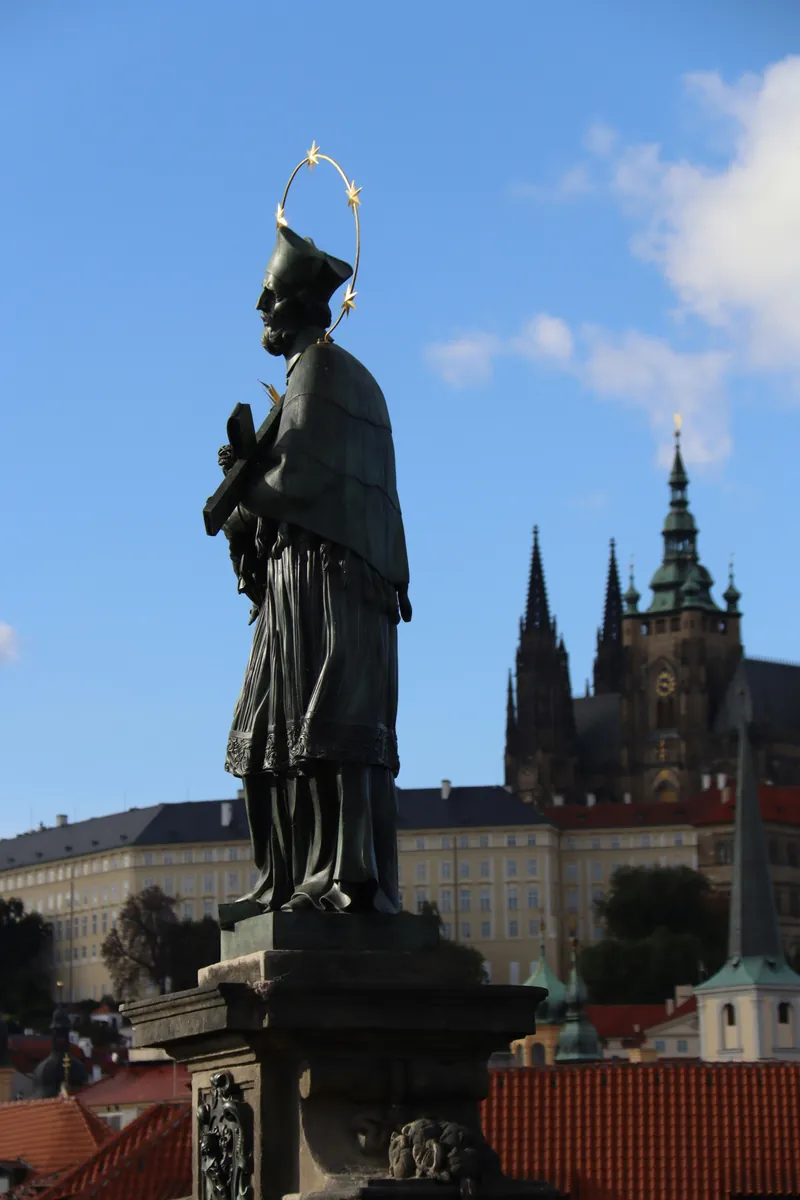 Die Statue des heiligen Johannes von Nepomuk mit Sternenkranz, dahinter der Veitsdom